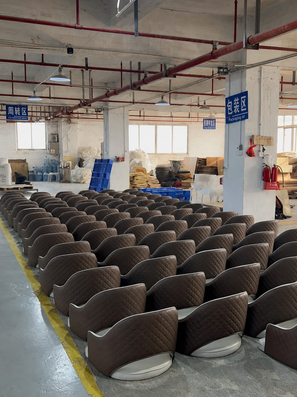 Quilted brown upholstered dining chairs arranged in rows in a furniture factory