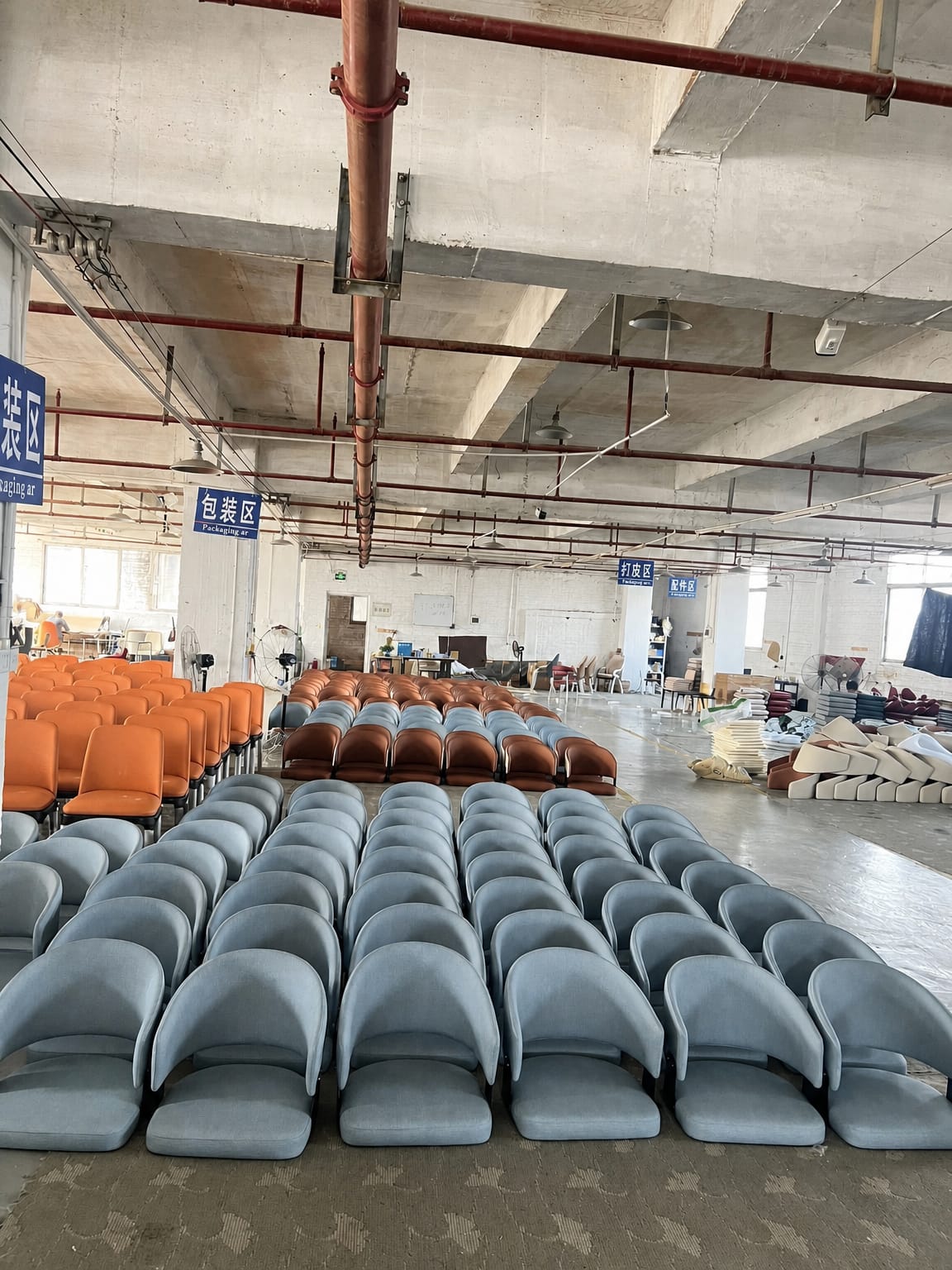 Rows of custom upholstered dining chairs in multiple colourways on a furniture factory floor