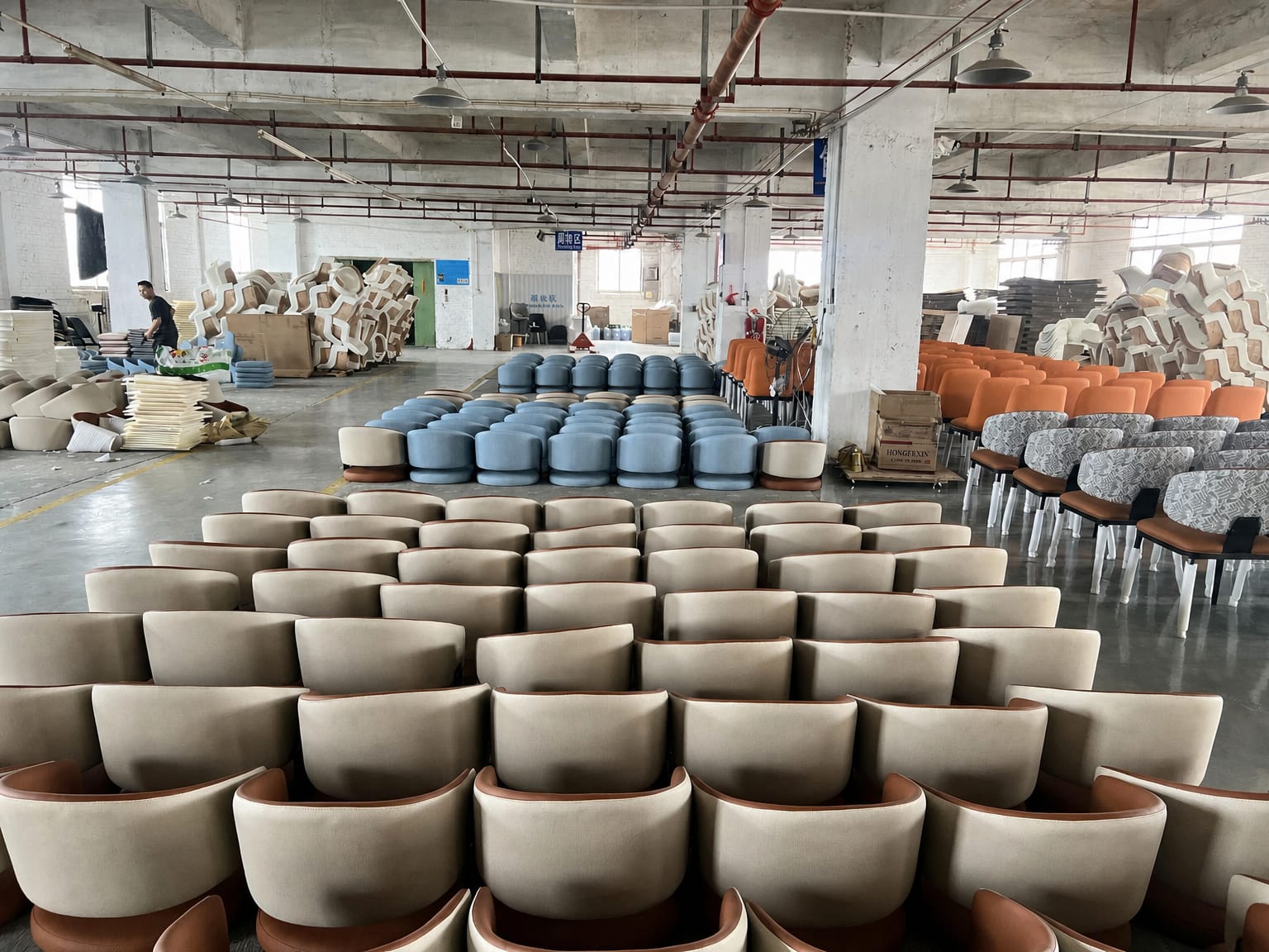 Neutral upholstered chairs and colourful seating arranged on a factory floor