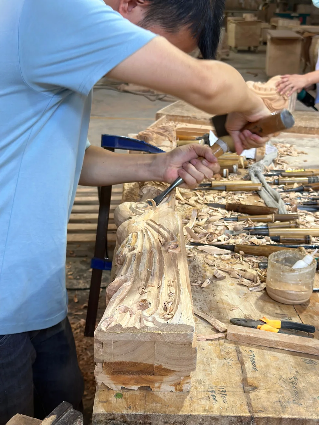 Chinese artisan hand-carving a decorative wood furniture detail in the workshop